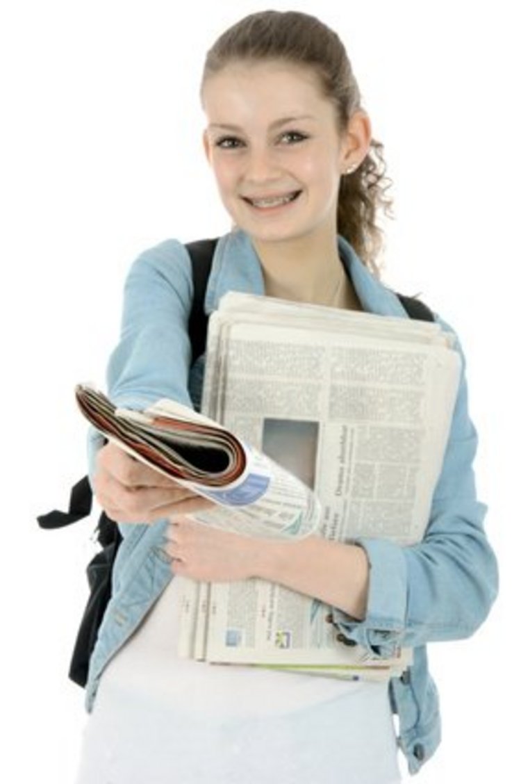Junge Frau stehend mit Zeitungen in beiden Händen